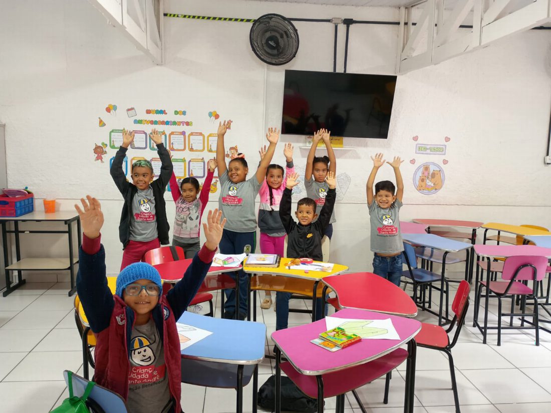 Crianças sorrindo com as mãos para o alto